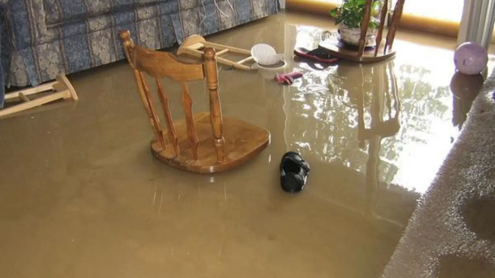 Living room with a wooden chair standing in murky floodwater